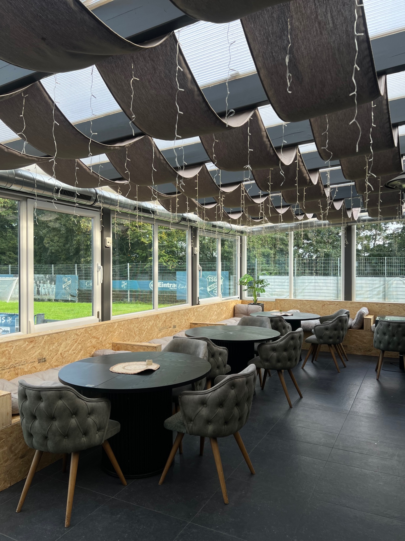 Wintergarten mit runden Tischen und Lichterketten